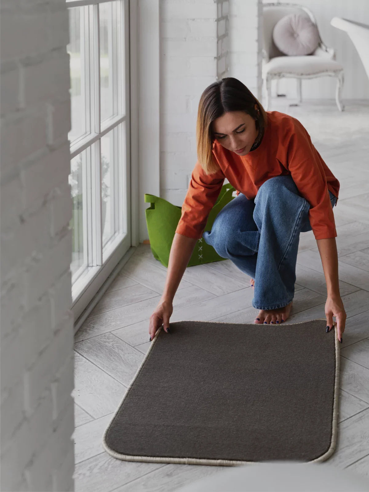 A woman placing a compact, machine-washable 2x3 rug on a bright, modern floor, showcasing its versatility and easy maintenance.
