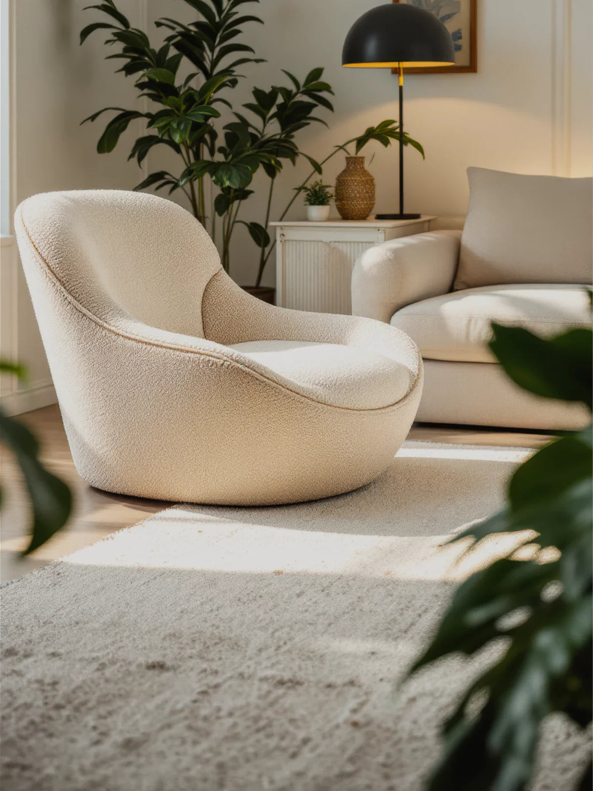 Modern living space featuring a soft cream & beige rug, a cozy boucle accent chair, and warm neutral decor with lush greenery for a serene ambiance.