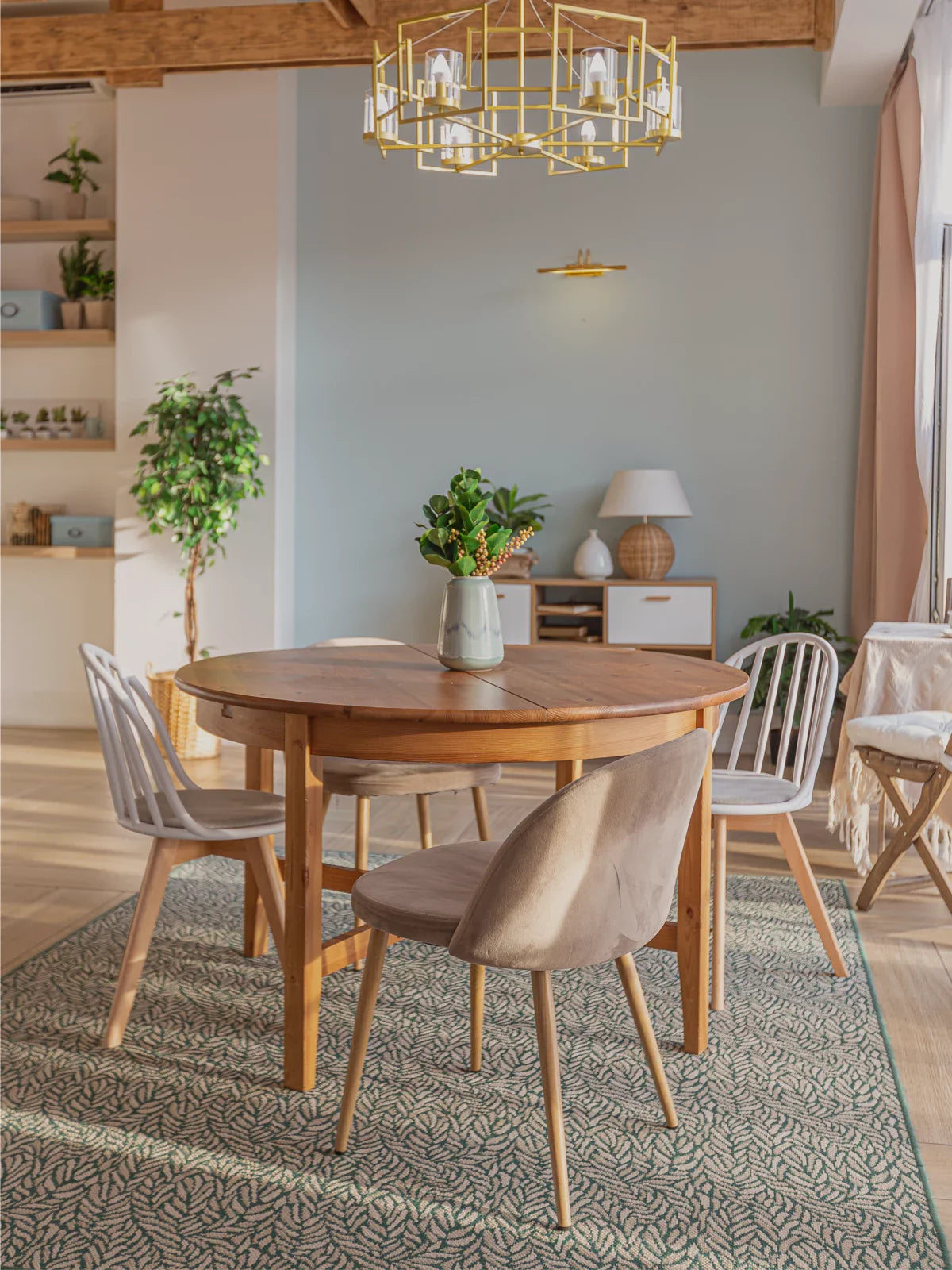 Stylish dining room featuring a round wooden table, modern chairs, and a patterned green rug, complemented by warm natural lighting and elegant decor.
