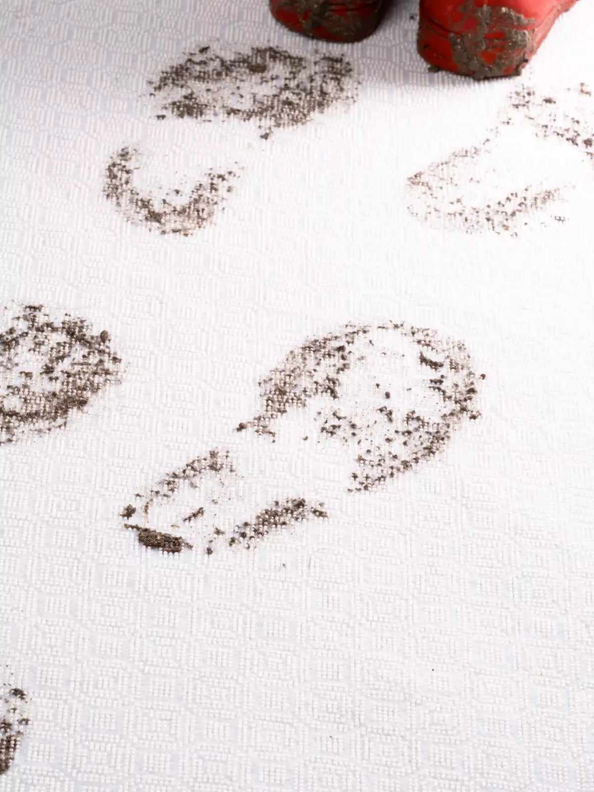 Coffee spilling from a white ceramic mug onto a patterned rug, demonstrating a common household accident on stain-resistant fabric.